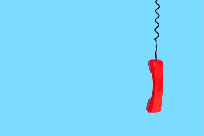 red corded landline telephone against blue background
