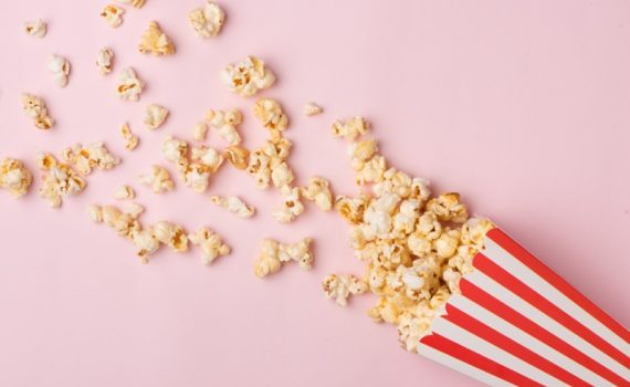 Popcorn in red and white cardboard box on the pink background