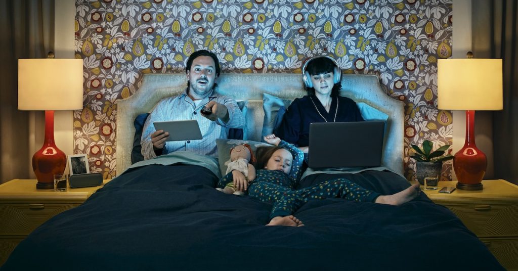 family in bed watching and streaming holiday movies