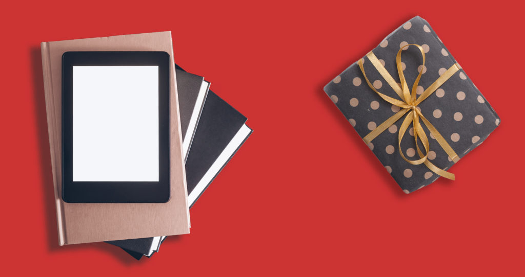 A tablet sitting on top of books next to a holiday gift