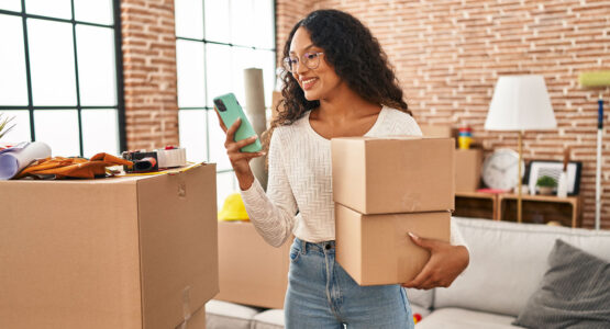 Woman holding some moving boxes looking at a phone